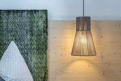 Room detail in Haus Gstrein featuring a wooden wall, an upholstered headboard, and a hanging lamp